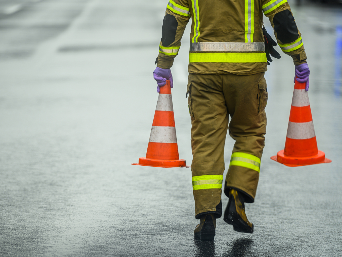 Firefighter holding traffic cones on roadway